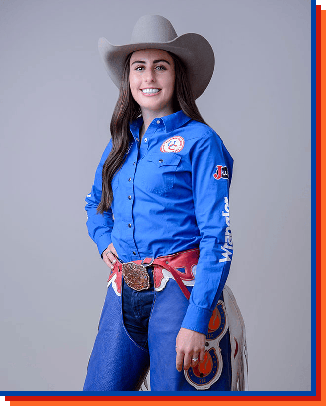 Bailey Holmes smiling at the camera, posing wearing a cowgirl hat and a blue shirt.